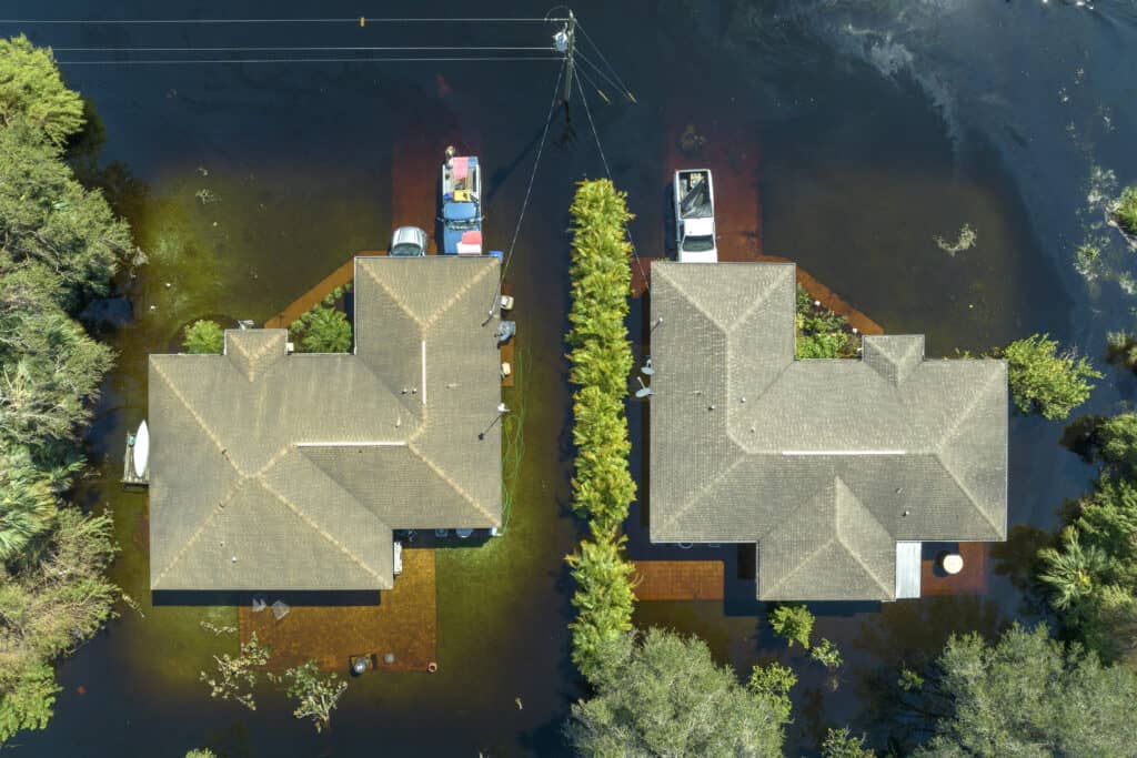 Flooded residential area with water encroaching on houses and vehicles.